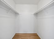 Thumbnail 16 of 18 - A white room with wooden floors and two white shelves.