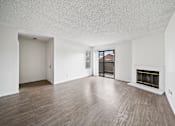 Thumbnail 13 of 18 - A large empty room with a fireplace and wood flooring.