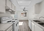 Thumbnail 3 of 11 - A white kitchen with a stove, sink, and a fan.