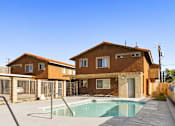 Thumbnail 1 of 11 - A house with a brown exterior and a pool in front.
