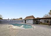 Thumbnail 6 of 9 - A small pool in a backyard with a building in the background.