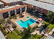 Thumbnail 15 of 70 - A swimming pool surrounded by a patio with chairs and umbrellas.