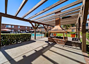 Thumbnail 18 of 70 - A patio with a table and chairs under a wooden pergola.