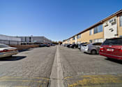 Thumbnail 23 of 70 - A parking lot with cars parked on both sides and apartment buildings in the background.