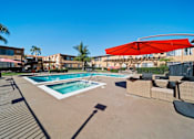 Thumbnail 27 of 70 - A pool with a red umbrella and a building in the background.