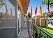 Thumbnail 29 of 70 - A balcony with a metal railing and a glass door leading to a patio with orange flags.