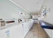 Thumbnail 37 of 70 - A laundromat with a row of washers and dryers.