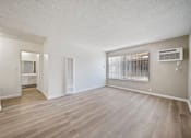Thumbnail 40 of 70 - A spacious room with wooden flooring and a window with blinds.