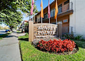Thumbnail 4 of 70 - Sunset Pointe Apartment Homes sign with red flowers in the foreground.
