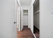 Thumbnail 53 of 70 - A white hallway with a door on the left and a refrigerator on the right.