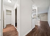 Thumbnail 54 of 70 - A long hallway with white walls and wood floors.