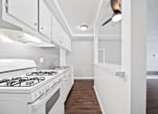 Thumbnail 56 of 70 - A white kitchen with a stove and a fan.