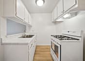 Thumbnail 60 of 70 - A white kitchen with a stove and sink.