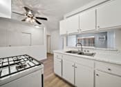 Thumbnail 61 of 70 - A kitchen with a white stove top oven and white cabinets.