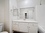 Thumbnail 65 of 70 - A white bathroom with a sink, mirror, and bathtub.