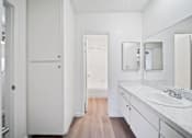 Thumbnail 66 of 70 - A white bathroom with a sink, mirror, and wooden floor.
