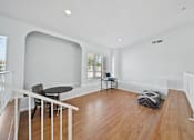 Thumbnail 10 of 10 - A room with a wooden floor and white walls has a table and chairs in it.