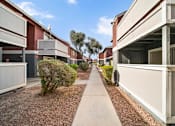 Thumbnail 2 of 13 - A long concrete walkway separates two rows of identical buildings.