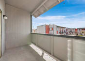 Thumbnail 17 of 21 - A balcony with white walls and a white ceiling with a view of a building in the background.