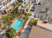 Thumbnail 6 of 21 - A swimming pool is surrounded by palm trees and a red tiled roof.