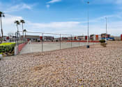 Thumbnail 3 of 21 - A gravel area with a fence and palm trees in the distance.