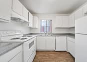 Thumbnail 20 of 21 - A white kitchen with wood floors and white appliances.
