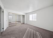 Thumbnail 9 of 17 - A room with a carpeted floor and a large mirror on the wall.