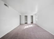 Thumbnail 1 of 17 - A large empty room with carpeted floor and white walls.