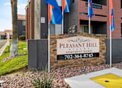 Thumbnail 3 of 17 - A sign for Pleasant Hill Village Apartments in front of a building.