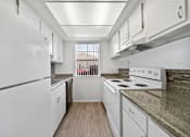 Thumbnail 14 of 17 - A kitchen with white appliances and wooden floors.