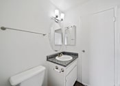 Thumbnail 11 of 11 - A white bathroom with a sink, toilet, and mirror.
