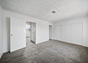 Thumbnail 3 of 11 - A spacious room with white walls and carpeted floor.