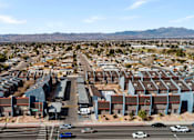 Thumbnail 4 of 11 - A large housing complex in a desert with mountains in the background.