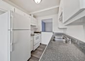 Thumbnail 8 of 11 - A white refrigerator is in a kitchen with a sink and a counter.