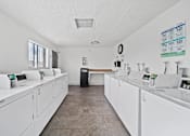 Thumbnail 6 of 11 - A laundromat with rows of washers and dryers.