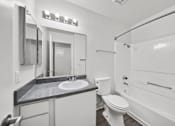 Thumbnail 19 of 21 - A bathroom with a toilet, sink, and mirror.