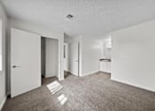 Thumbnail 12 of 21 - A white room with a carpeted floor and a white door.