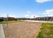 Thumbnail 4 of 21 - A fenced-in area with a dirt ground and a building in the background.