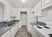 Thumbnail 17 of 21 - A kitchen with white cabinets and a stove top oven.