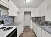 Thumbnail 20 of 21 - A kitchen with white cabinets and a stove top oven.