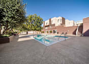 Thumbnail 17 of 75 - A pool in a courtyard surrounded by trees and buildings.
