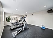Thumbnail 22 of 75 - A room with a treadmill, exercise bike, and weights.