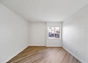 Thumbnail 31 of 75 - Empty room with wooden floor and white walls.