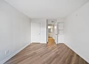 Thumbnail 32 of 75 - A long hallway with white walls and wood floors.