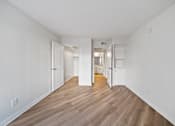 Thumbnail 33 of 75 - A long hallway with white walls and wood flooring.