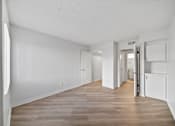 Thumbnail 34 of 75 - A long, empty hallway with white walls and wood flooring.