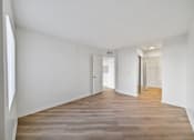 Thumbnail 36 of 75 - A long, empty hallway with wood flooring and white walls.