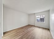 Thumbnail 40 of 75 - Empty room with wooden flooring and a window with bars.