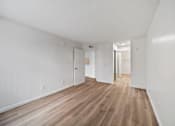 Thumbnail 41 of 75 - A long hallway with white walls and wood flooring.