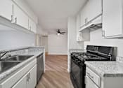 Thumbnail 46 of 75 - A kitchen with a black stove top oven and a sink with a granite counter top.